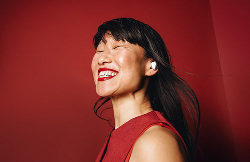 Woman enjoying immersive sound with earbuds in vibrant red portrait