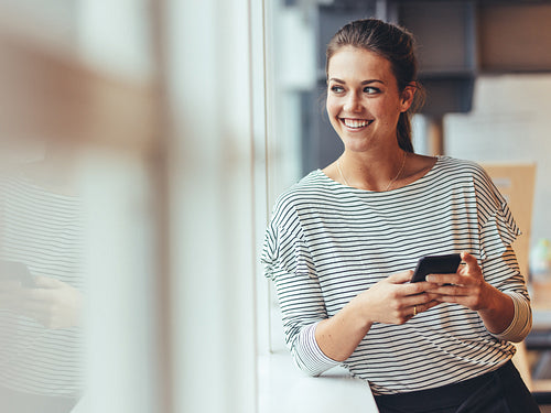 Woman looking out of a window standing in office
