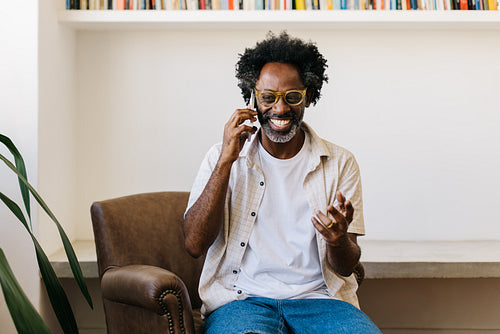 Mature black man using smartphone for a phone call in living room