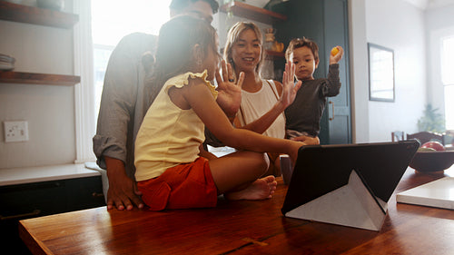 Happy family having a video chat with their loved ones on a tablet at home