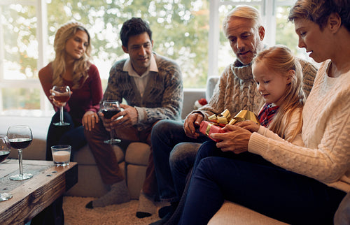 Little girl with family opening christmas gifts