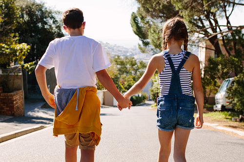 Rear view of kids walking on road holding hands