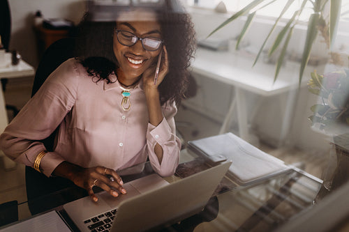 Woman making notes working on laptop at home