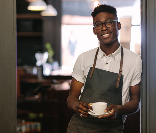 Café owner at his coffee shop holding a coffee cup