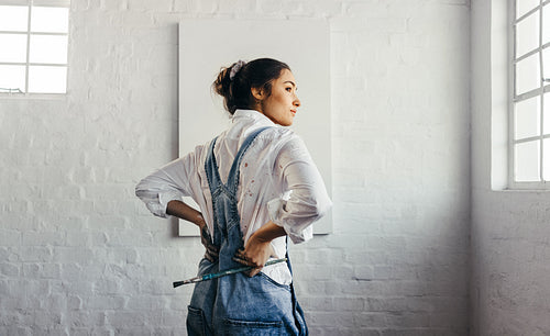 Painter looking away thoughtfully in her studio