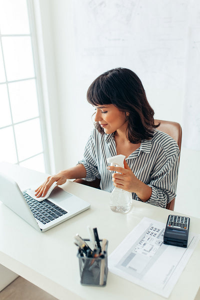 Woman disinfecting her work desk