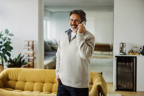 Senior man talks on a smartphone at home