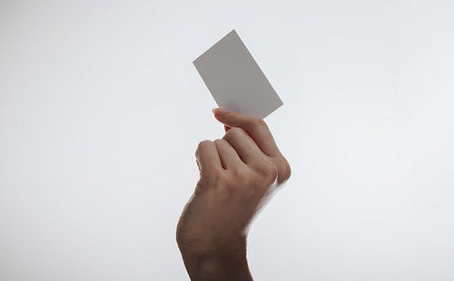 Hand holding a blank card against a simple white background