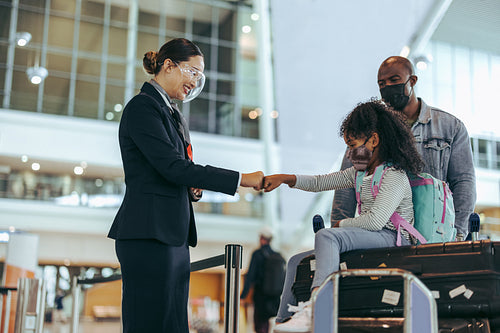 Airport staff greeting small girl with fist bump