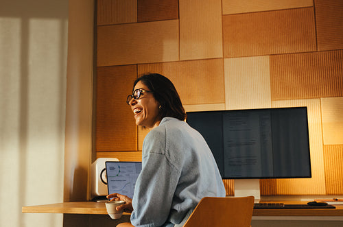 Woman enjoys coffee while working with a laptop in a warm office