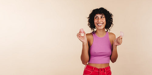 Young woman holding a menstraul cup and a menstrual disc in her