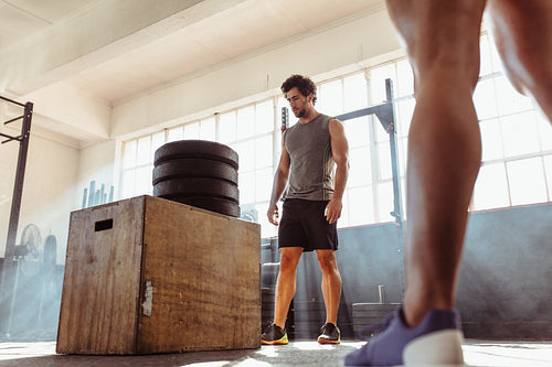 Determined fit man doing box jumping in health club