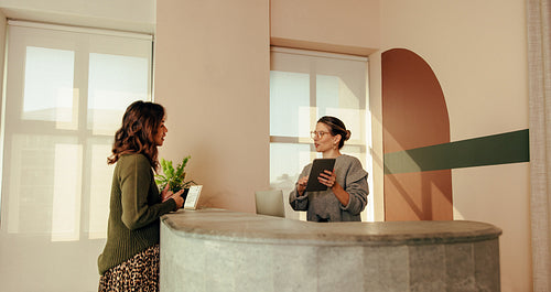 Front desk administrator assisting a woman with signing in to an