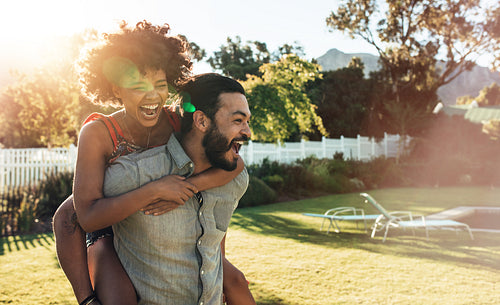 Young couple piggybacking in backyard