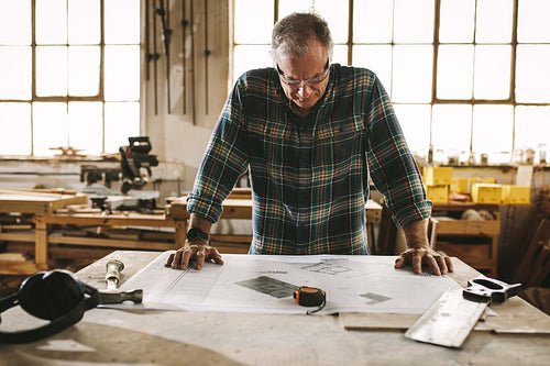 Senior carpenter checking drawing in workshop