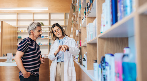 Female pharmacist assisting a man in a drug store