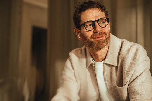 Businessman sits for a work portrait with glasses and earbuds