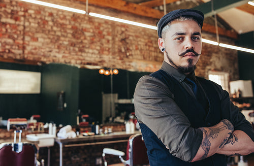 Serious looking young man standing at barber shop