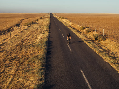 Professional cyclist on countryside landscape road