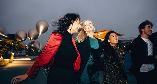 Group of friends celebrating outdoors at night with balloons and joy