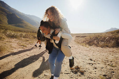 Friends piggybacking and laughing together on mountain hike