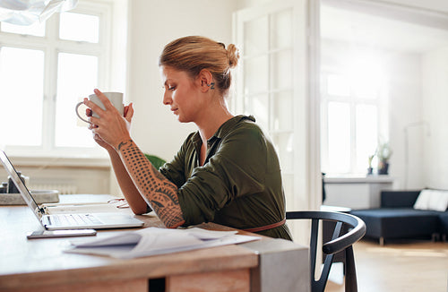 Thoughtful young woman with coffee sitting at table