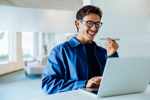 Man with glasses smiles while using laptop