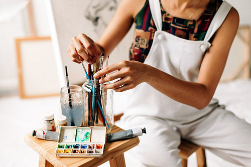 Unrecognizable female painter picking a brush from a jar