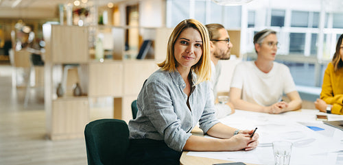 Confident young designer sitting in a meeting with her team