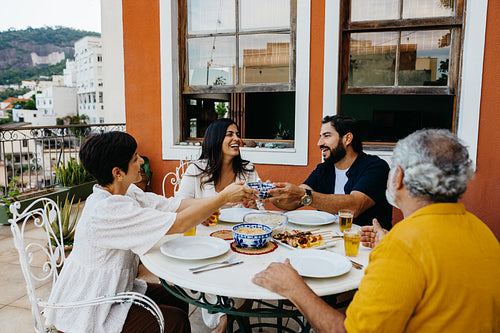 Family gathering enjoying a meal on a terrace in a scenic setting