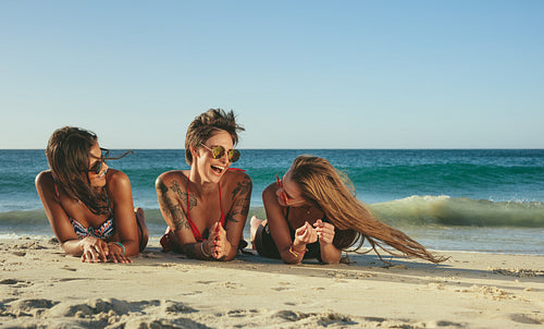 Woman friends relaxing at the beach and talking