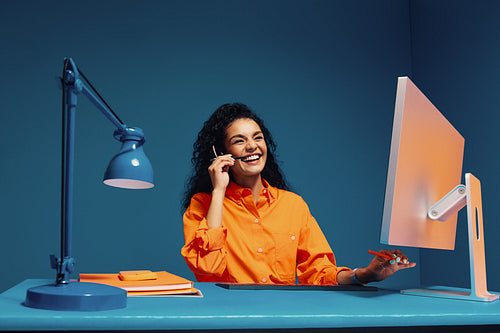 Customer service agent in office using headset and computer with color blocking bright clothes