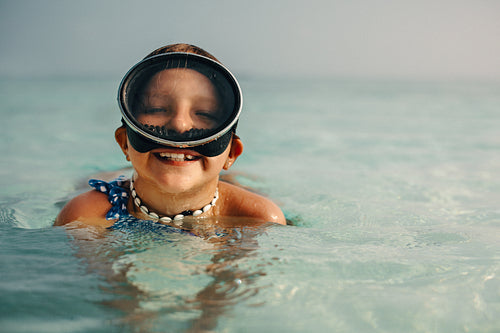 Island adventure: Joyful young girl in snorkeling gear swimming in crystal-clear sea