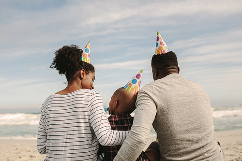Family with party hats blowing whistle on the beach