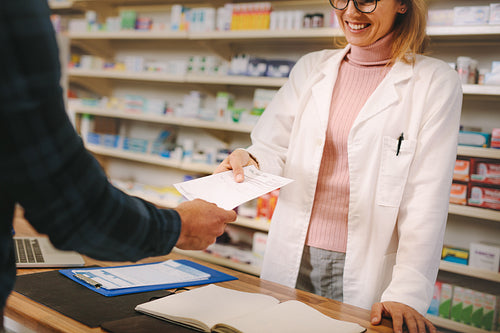 Customer giving prescription to pharmacist in pharmacy