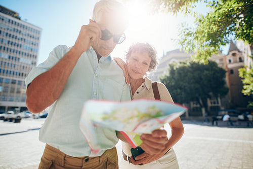 Couple outdoors in city reading a map for direction