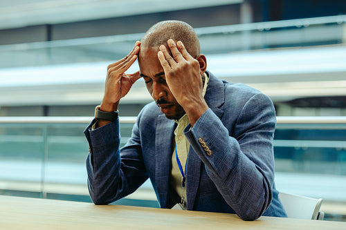 Frustrated businessman holding head in modern office setting