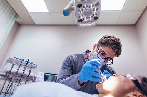 Stomatologist treating teeth of patient in clinic