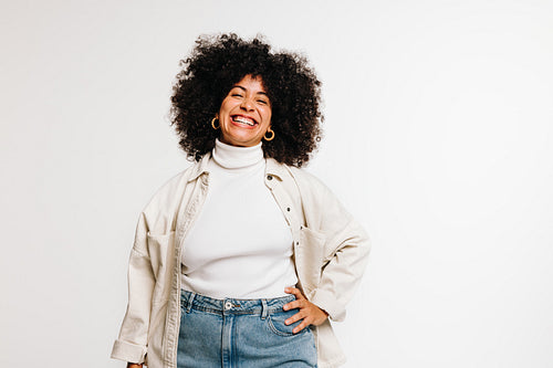 Joyful woman with curly hair smiling at the camera in a studio