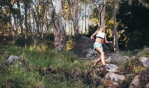 Woman athlete running in a dense park