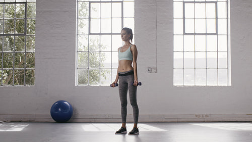 Woman doing biceps curls with dumbbells at fitness studio