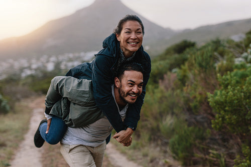 Couple enjoying piggyback ride in countryside