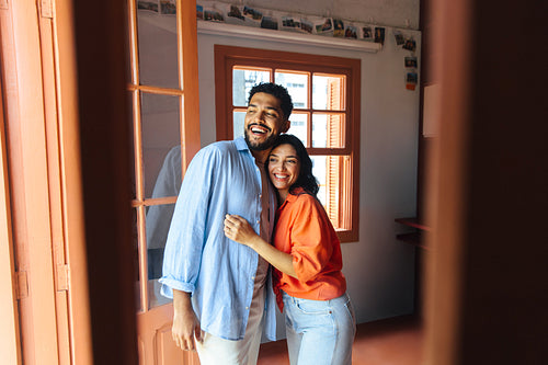 Happy Latin American couple standing together in a bright cozy living space