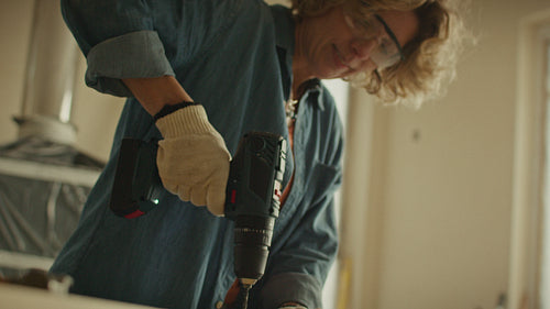 Crafting a vision: Woman uses power drill during home renovation project