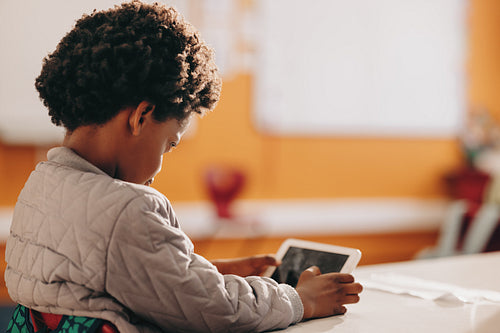 Focused little boy using a tablet in class