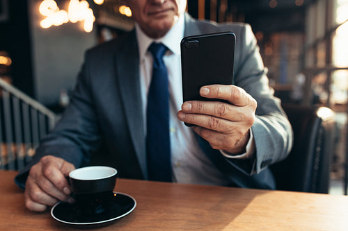 Senior businessman using smartphone at coffee shop
