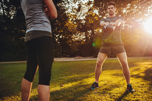 Young man doing kettlebell workout with personal trainer