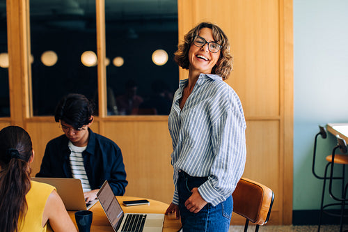Smiling woman working in a casual office environment with colleagues around
