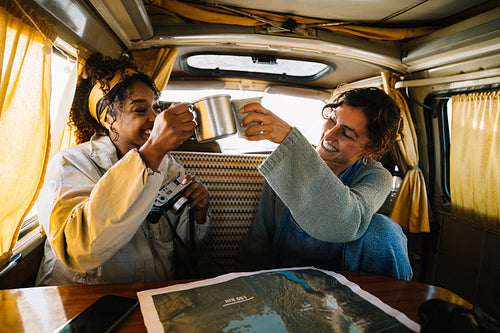 Friends toast mugs in a camper van during a road trip