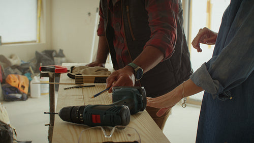 Couple planning home renovation using a drill and measurement tool